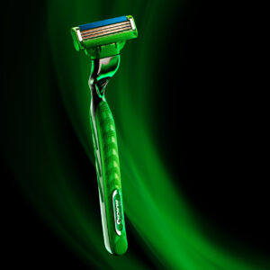 Creative photograph of a Gillette Mach3 razor with a sleek green and chrome design, illuminated with vibrant green lighting effects against a dark background. Captured as part of a creative pitch by Steve Hirsch.