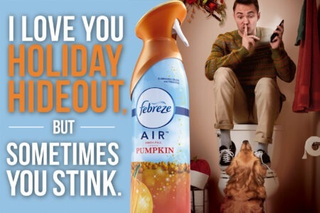 A humorous Febreze ad photographed by Steve Hirsch, featuring a man hiding on a toilet during a holiday gathering, using his phone while a dog looks up at him. A can of Febreze Pumpkin Air Freshener is prominently displayed.